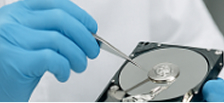 Mani con guanti azzurri che tengono un hard disk aperto per diagnostica